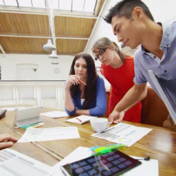 Team collaborating over documents and a tablet.