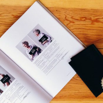 Open book with photographs on wooden table.