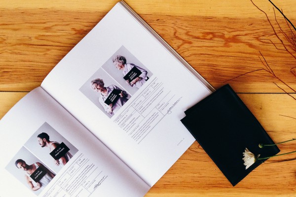 Open book with photographs on wooden table.