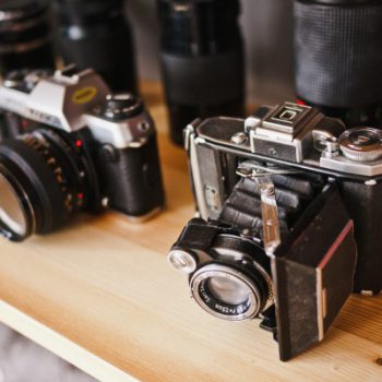 Vintage cameras displayed on a wooden shelf.