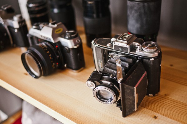 Vintage cameras displayed on a wooden shelf.