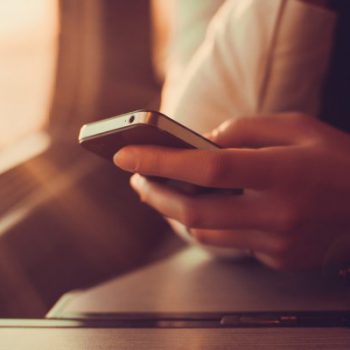 Person holding smartphone near window seat.