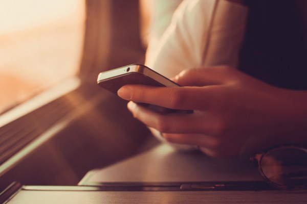 Person holding smartphone near window seat.